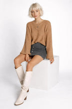 Model sitting while wearing Hollowed Detail Wide Sleeve Loose Pullover Sweater